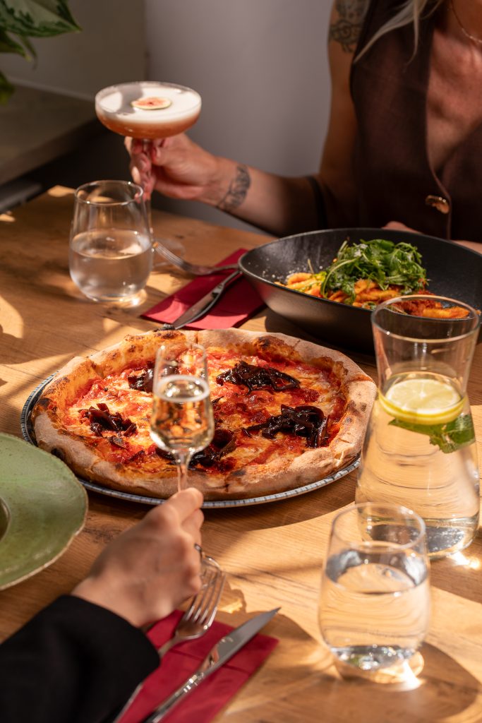 Rzemieślnicza pizza, sałatka i drink na drewnianym stole w restauracji La Tropea