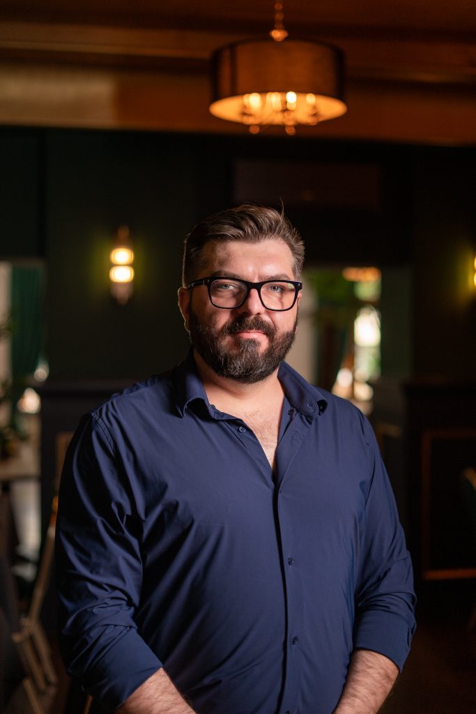 Portret mężczyzny w granatowej koszuli we wnętrzu restauracji La Tropea o zmroku